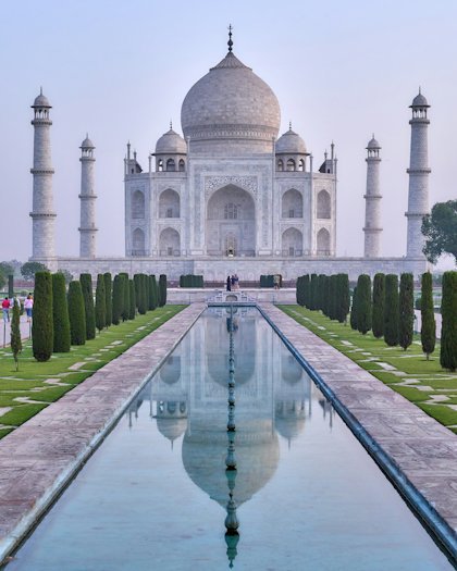 The Taj Mahal reflected in its long ornamental pool at dawn