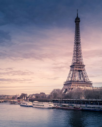 The Eiffel Tower above the rooftops of Paris at dusk