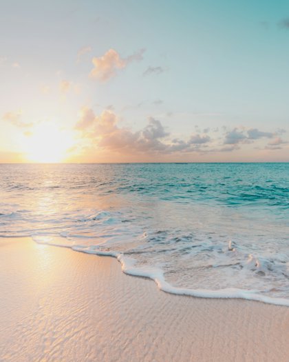 Calm turquoise sea meeting a quiet tropical shoreline at sunset