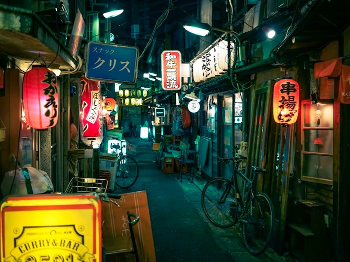 Neon signs lighting a narrow lane in Tokyo at night