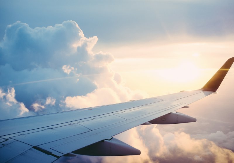 An aircraft wing above a bank of cloud at sunset