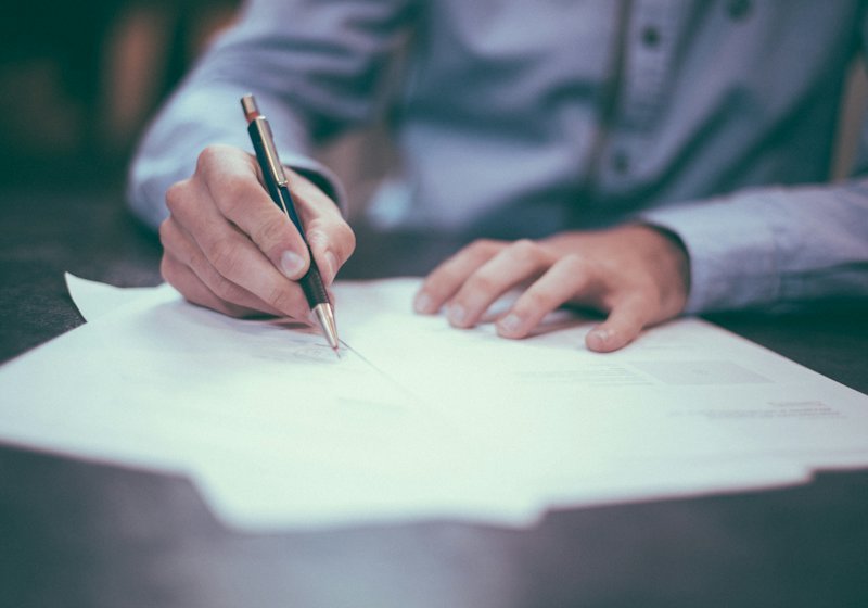 Hands completing travel paperwork with a pen